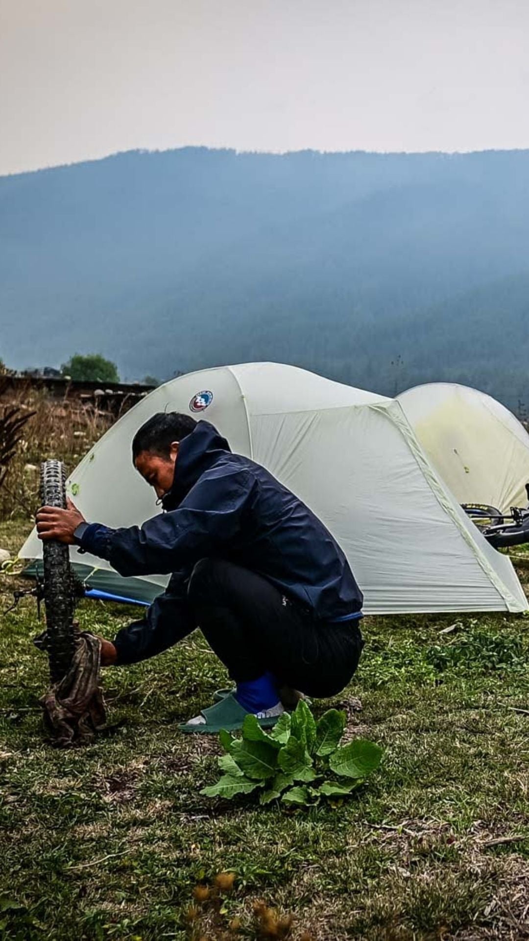 Person setting up a tent in a mountainous area