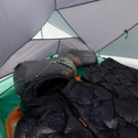 Black sleeping bag inside a tent with camping gear visible